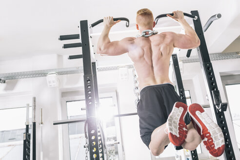 Junger Mann übt Klimmzüge auf dem Power Rack im Fitnessstudio - MADF000220