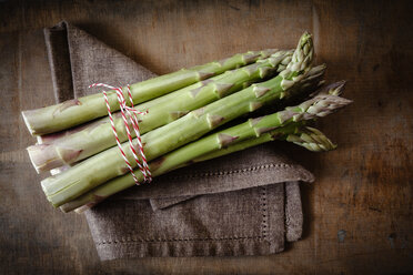 Bündel grüner Spargel auf Tuch und Holz - EVGF001673