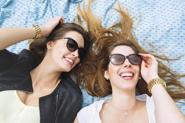 Zwei lachende Frauen mit Sonnenbrille auf blauem Sarong liegend - GEMF000240