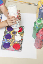 Boy's hand pressing paint bottle in an art class - ZEF005007