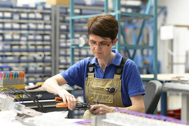Arbeiter, der in einer Fabrik für den Bau von Schaltanlagen Kabel konfektioniert - LYF000422