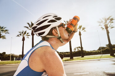 Spanien, Mallorca, Sa Coma, Porträt eines Triathleten, der auf dem Fahrrad Wasser trinkt - MFF001606