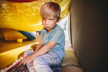 Porträt eines kleinen Jungen, der in einer Deckenhöhle sitzt und ein lustiges Gesicht macht - MFF001582