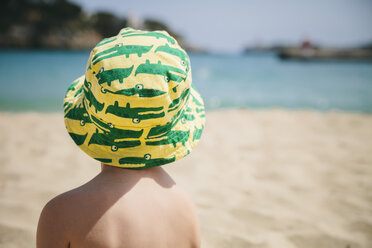 Spanien, Mallorca, Porto Christo, Rückenansicht eines kleinen Jungen, der am Strand sitzt und einen Sommerhut trägt - MFF001587