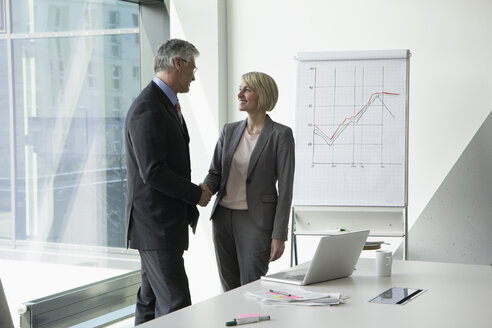 Businissman and businesswoman shaking hands in conference room - RBF002660