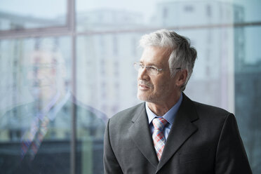 Geschäftsmann steht am Fenster und schaut in die Ferne - RBF002663