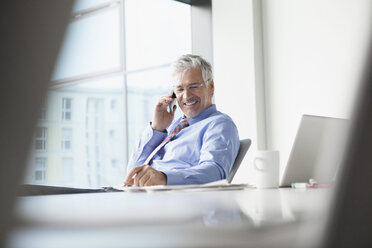 Businessman sitting at desk, talking on the phone - RBF002680