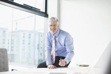 Businessman sitting at desk preparing presentation - RBF002687