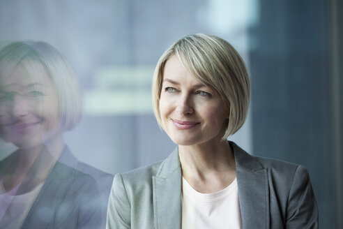 Geschäftsfrau stehend am Fenster, lächelnd, Porträt - RBF002688