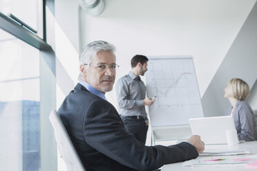 Businessman in meeting listening to presentation - RBF002707