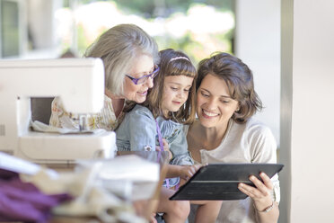 Mother, daughter and grandmother working on sewing machine - ZEF004842