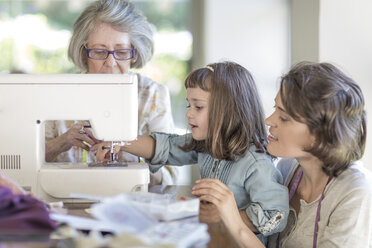 Mother, daughter and grandmother working on sewing machine - ZEF004845