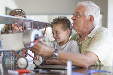 Großvater und Enkelkinder beim Aufbau eines Modellflugzeugs - ZEF004853