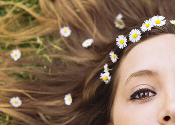 Woman lying on a meadow wearing daisies in her hair, close-up - GEMF000233