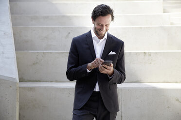 Businessman using smartphone in a modern building - FMKF001520