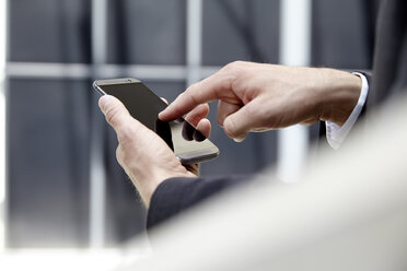 Die Hände eines Geschäftsmannes berühren den Bildschirm seines Smartphones - FMKF001523