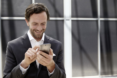 Geschäftsmann mit Smartphone in einem modernen Gebäude, lizenzfreies Stockfoto