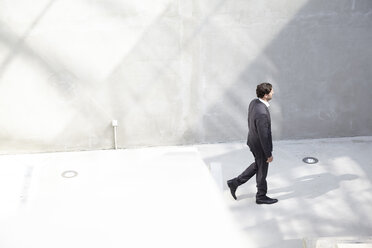 Businessman walking in a modern building - FMKF001553