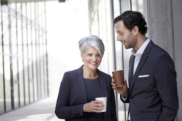 Two smiling business people with coffee to go - FMKF001538