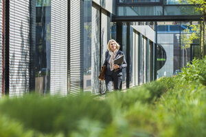 Nature businesswoman carrying briefcase and files - UUF004090