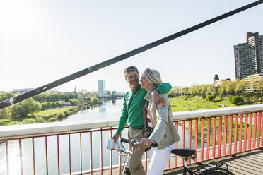 Deutschland, Mannheim, Älteres Paar überquert Brücke, schiebt Fahrrad - UUF004142