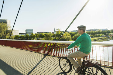 Germany, Mannheim, Mature man cycling over bridge - UUF004145