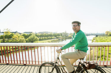 Germany, Mannheim, Mature man cycling over bridge - UUF004158