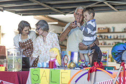 Eine Drei-Generationen-Familie veranstaltet einen Flohmarkt, lizenzfreies Stockfoto