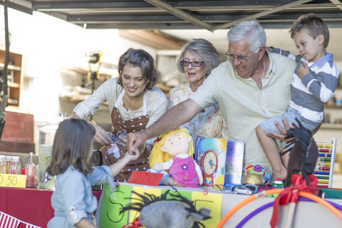 Eine Drei-Generationen-Familie veranstaltet einen Flohmarkt, lizenzfreies Stockfoto