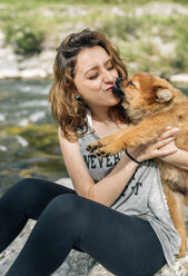 Porträt einer jungen Frau, die mit einem Pomeranian-Welpen kuschelt - MGOF000766