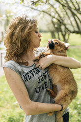 Junge Frau, die mit einem Pomeranian-Welpen kuschelt - MGOF000768