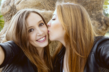 Young woman taking a selfie while her female friend kissing her on the cheek - GEMF000235