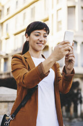 Spanien, Barcelona, lächelnde Geschäftsfrau macht Selfie mit Smartphone - EBSF000600