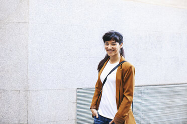 Lächelnde Geschäftsfrau vor einer Fassade - EBSF000601