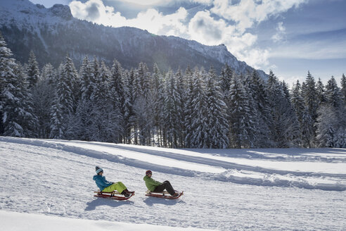 Deutschland, Bayern, Inzell, Paar auf Schlitten in schneebedeckter Landschaft - FFF001441