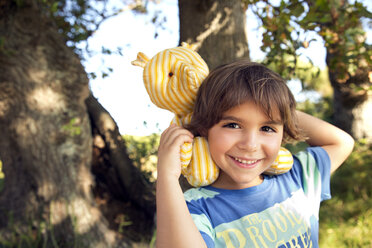 Portrait of smiling boy with cuddly toy outdoors - TOYF000254