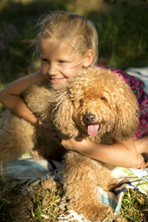 Glückliches Mädchen, das einen Hund auf einer Decke umarmt - TOYF000258