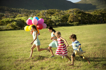 Happy children running with balloons on meadow - TOYF000266