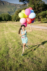 Glückliches Mädchen läuft mit Luftballons auf einer Wiese - TOYF000269