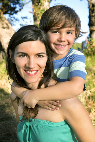 Happy mother carrying son piggyback stock photo