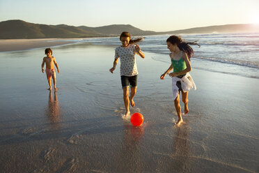 Three children playing with ball at the ocean - TOYF000294