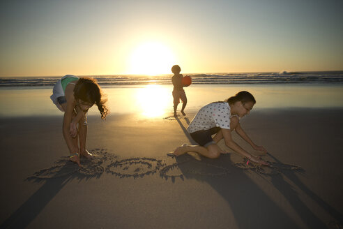 Kinder am Strand bei Sonnenuntergang malen im Sand - TOYF000278