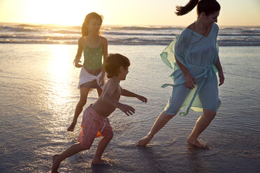 Familie spielt bei Sonnenuntergang am Strand - TOYF000283