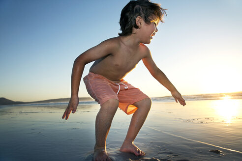 Junge spielt am Strand bei Sonnenuntergang - TOYF000285