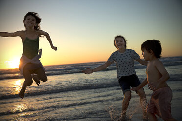 Drei Kinder spielen bei Sonnenuntergang am Strand - TOYF000286