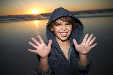 Porträt eines verspielten Jungen am Strand bei Sonnenuntergang - TOYF000289