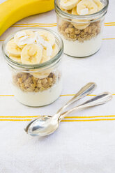 Glasses of natural yoghurt, granola, banana slices and coconut flakes - LVF003312