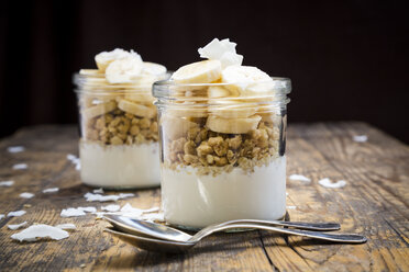 Glasses of natural yoghurt, granola, banana slices and coconut flakes - LVF003313