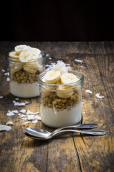 Glasses of natural yoghurt, granola, banana slices and coconut flakes - LVF003314