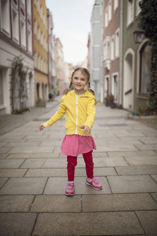 Deutschland, Bayern, lächelndes kleines Mädchen in einer Gasse stehend, lizenzfreies Stockfoto